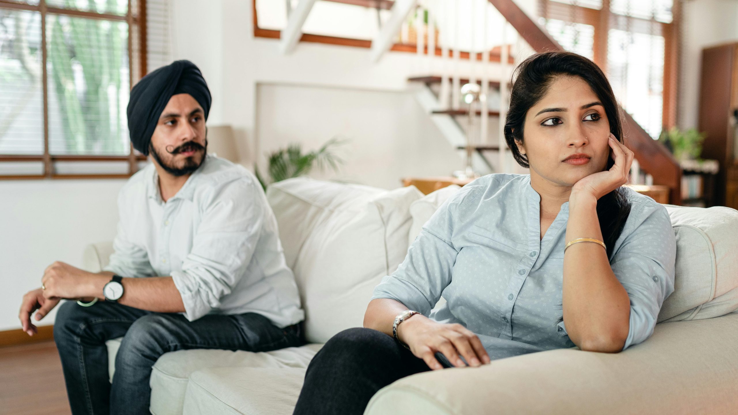 Upset young couple having argument while sitting on couch